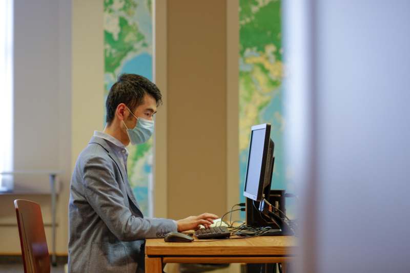 a man wearing a mask and using a computer