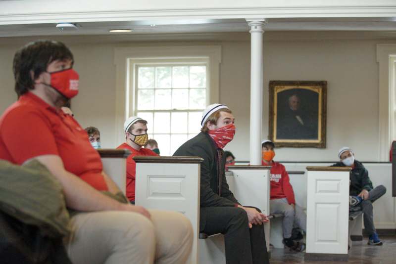 a group of people sitting in a room with masks