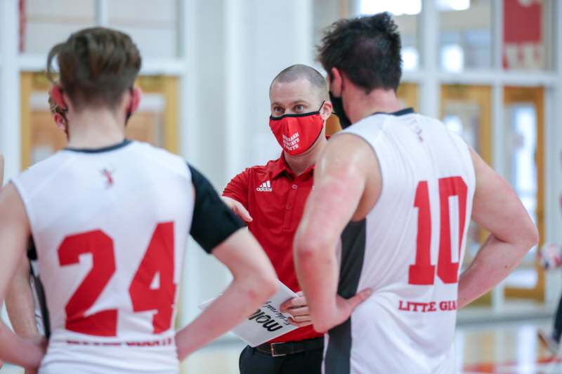 a man wearing a face mask talking to a basketball player