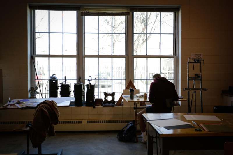 a man sitting at a desk in a room with a window