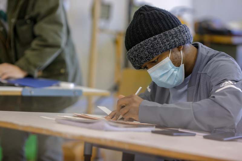 a man wearing a face mask writing on a piece of paper