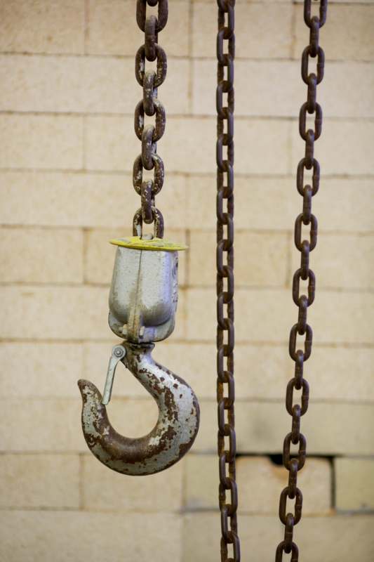a chain and hook with a brick wall behind it