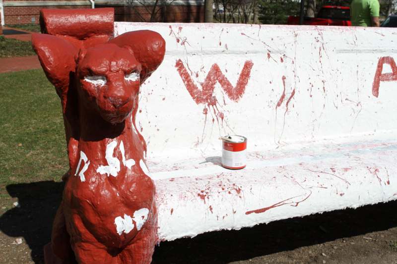 a red painted animal statue on a white bench