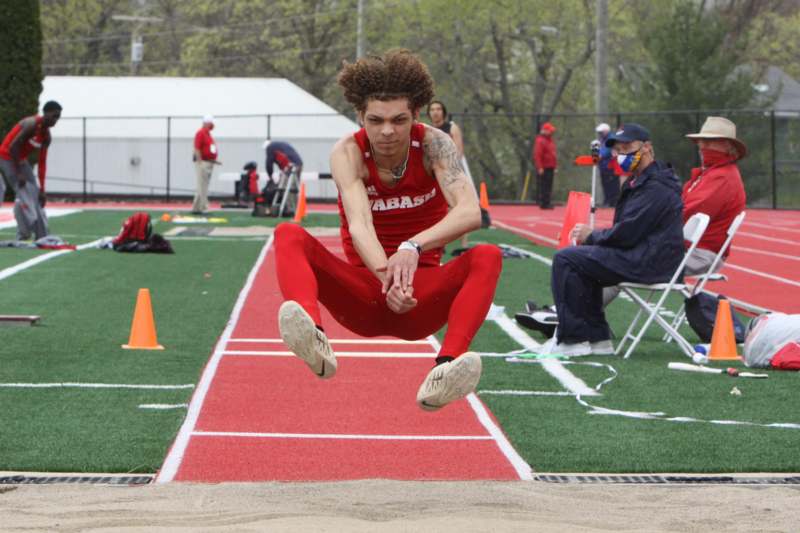 a man in red pants jumping over a long jump
