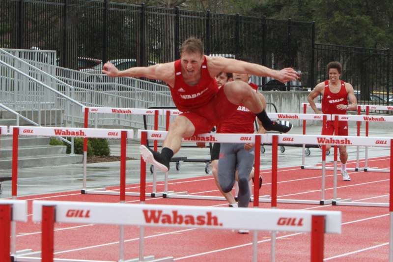 a group of men jumping over hurdles
