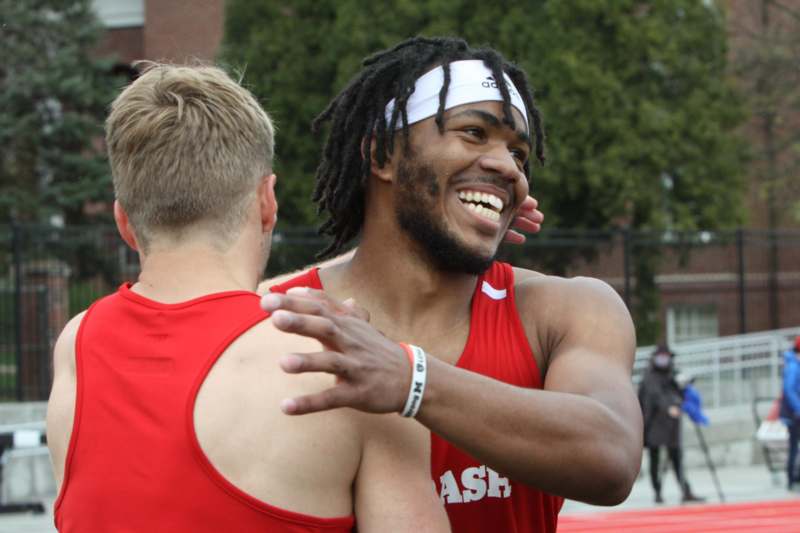 a man in red tank top hugging another man
