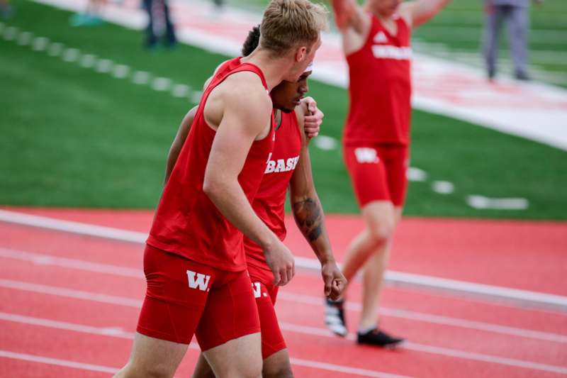 a group of men in red uniforms on a track