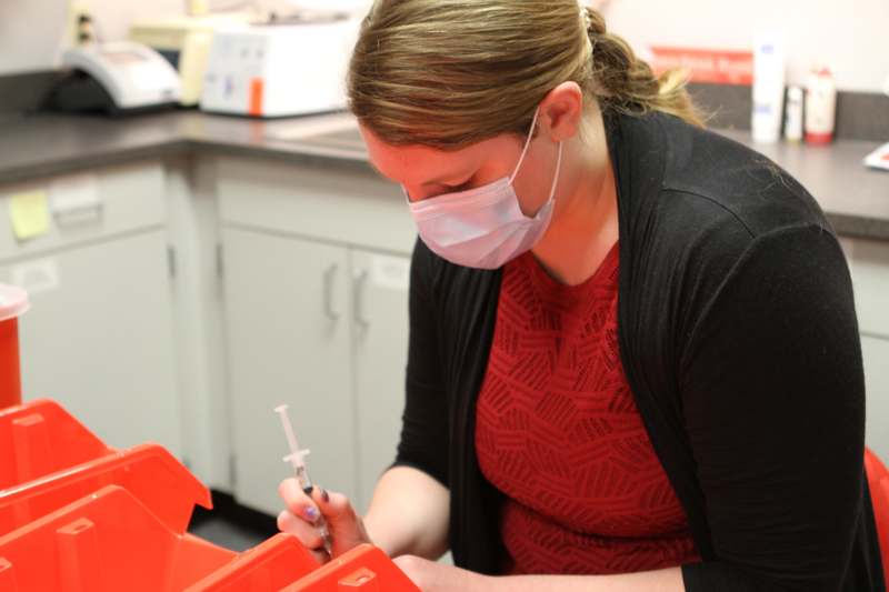 a woman wearing a mask and holding a syringe