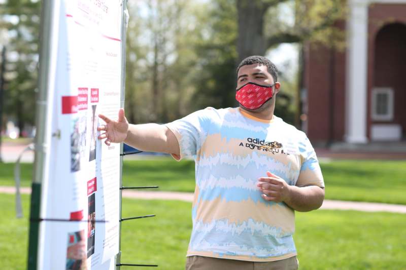 a man wearing a face mask pointing at a sign