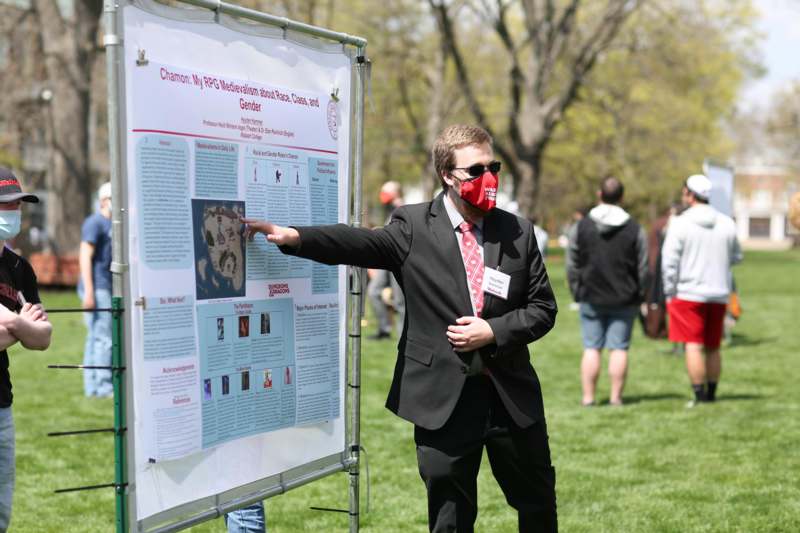 a man wearing a suit and tie pointing at a poster