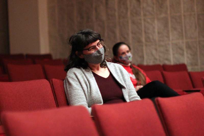 a woman wearing a mask sitting in a theater