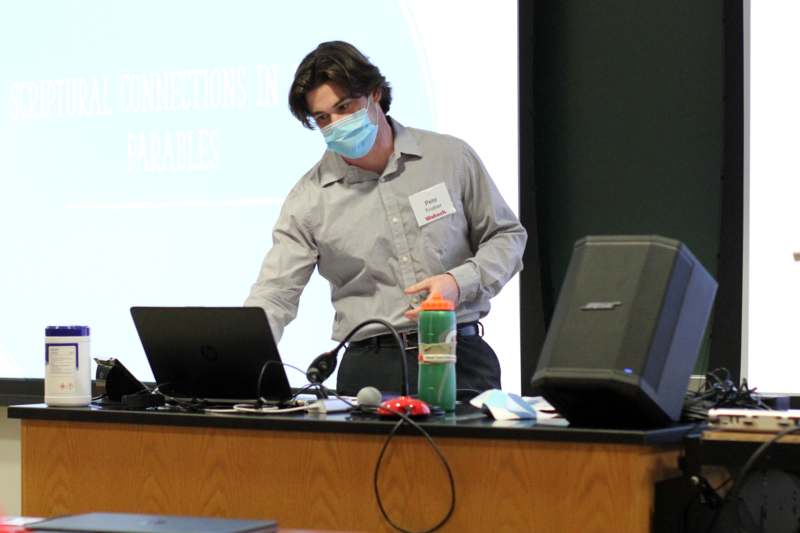 a man wearing a mask and standing in front of a laptop