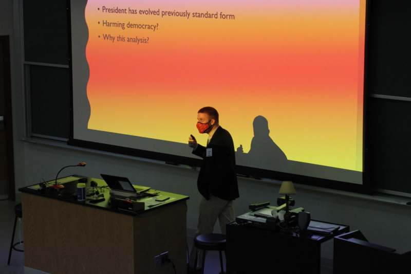 a man wearing a mask in front of a projector screen