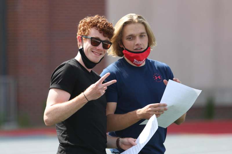 two men wearing face masks and holding papers