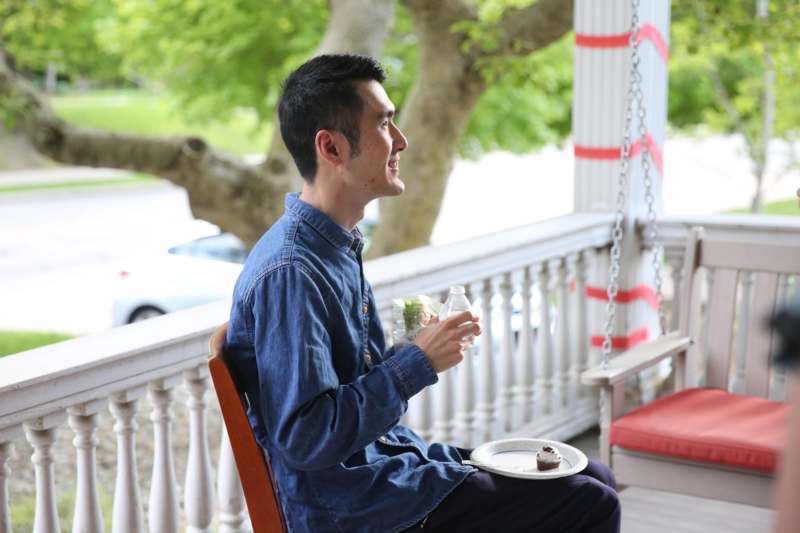 a man sitting on a porch with a plate of food