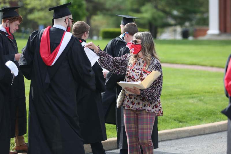 a woman wearing a mask and holding a diploma