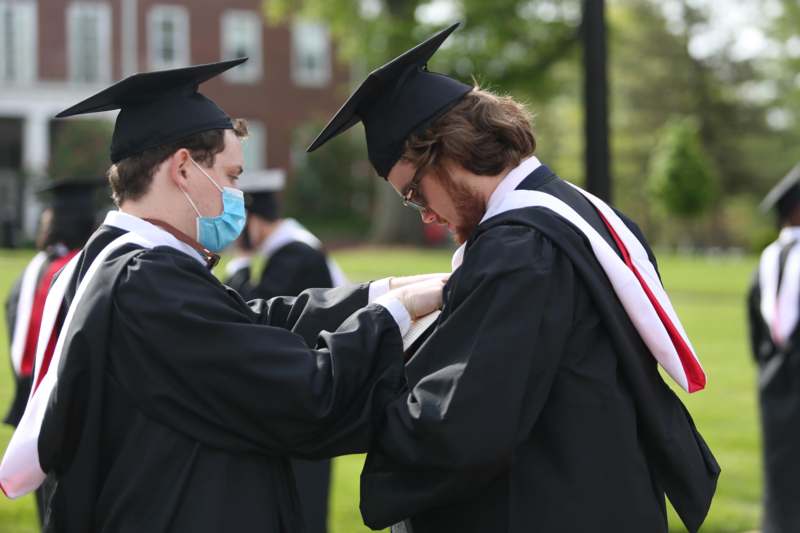 a man wearing a mask and a cap and gown