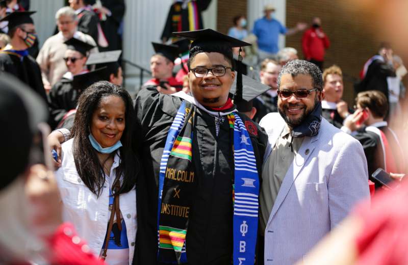 a man in a graduation cap and gown with a woman in a crowd