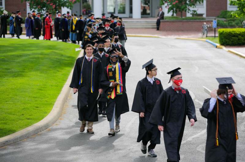 a group of people in graduation gowns and caps walking down a road