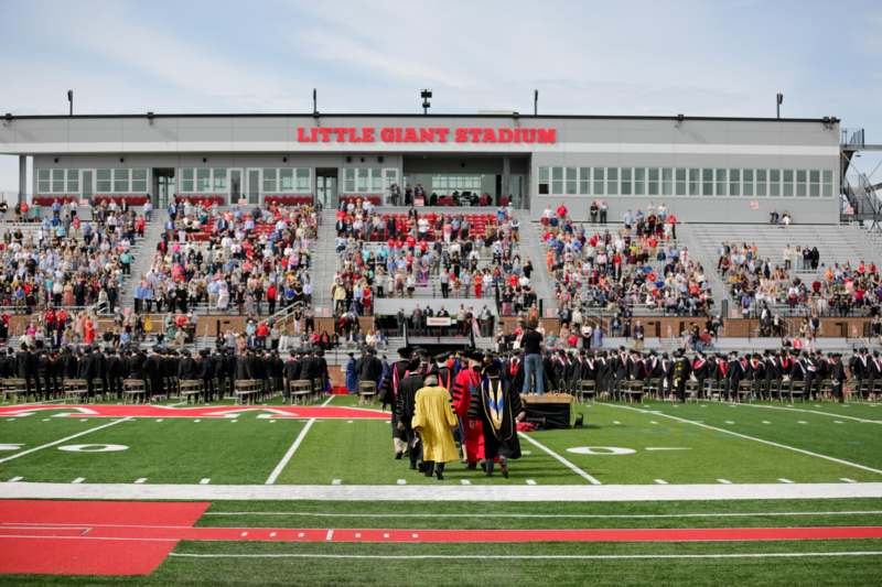 a group of people in graduation gowns on a football field