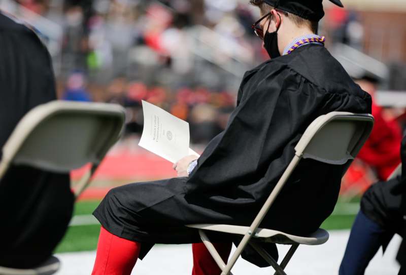 a man in a graduation gown sitting in a chair
