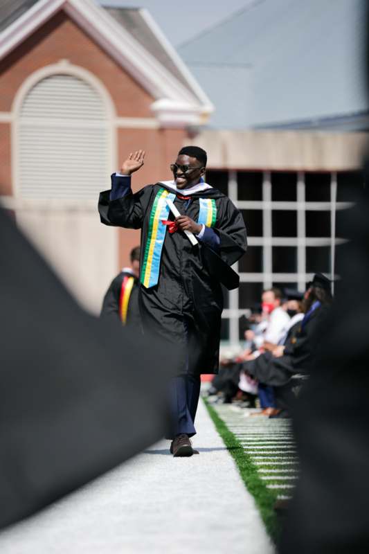 a man in a graduation gown waving