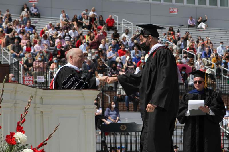 a man shaking hands with a man in a cap and gown