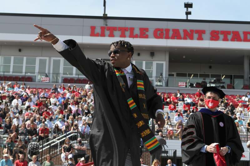 a man in a graduation gown pointing his finger