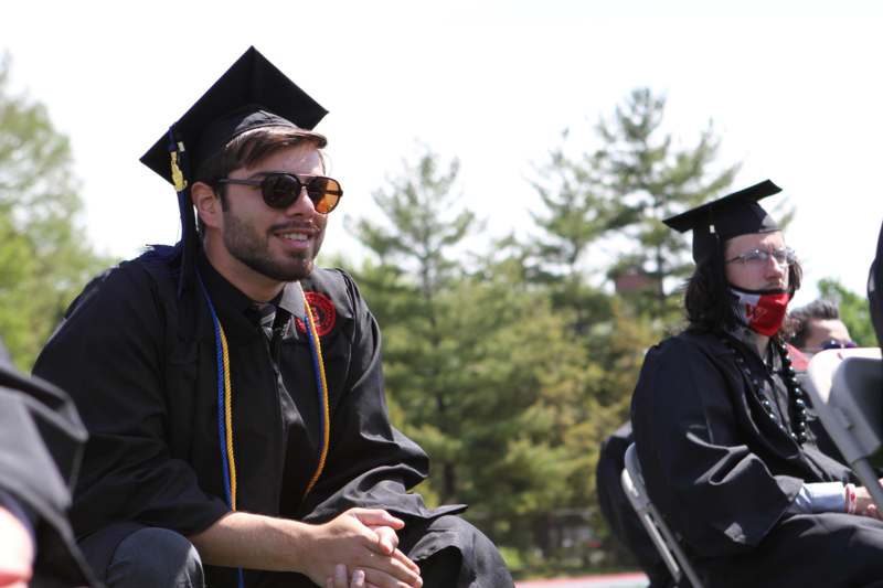 a man in a cap and gown sitting in a chair