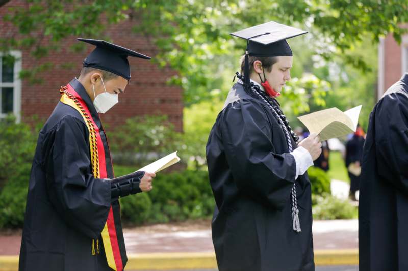 a group of people in graduation gowns and masks