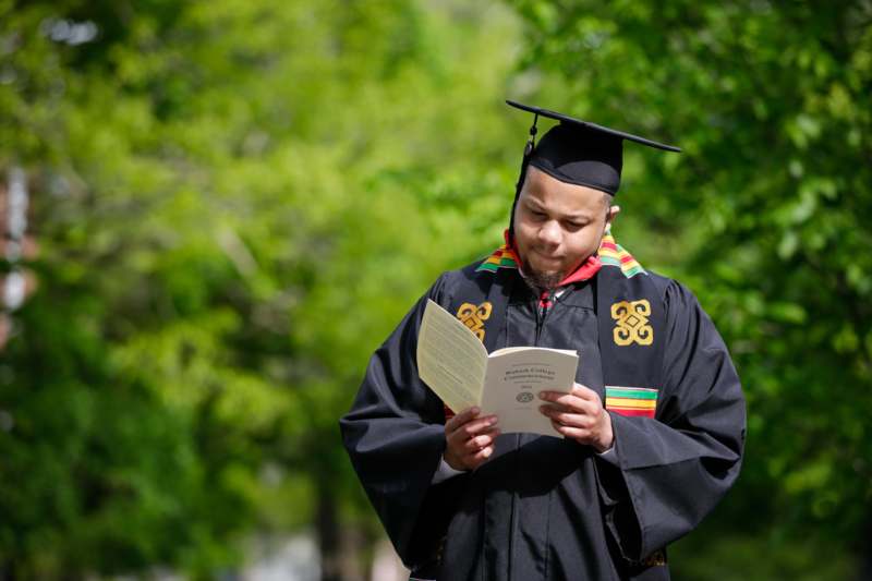 a man in a graduation gown reading a book