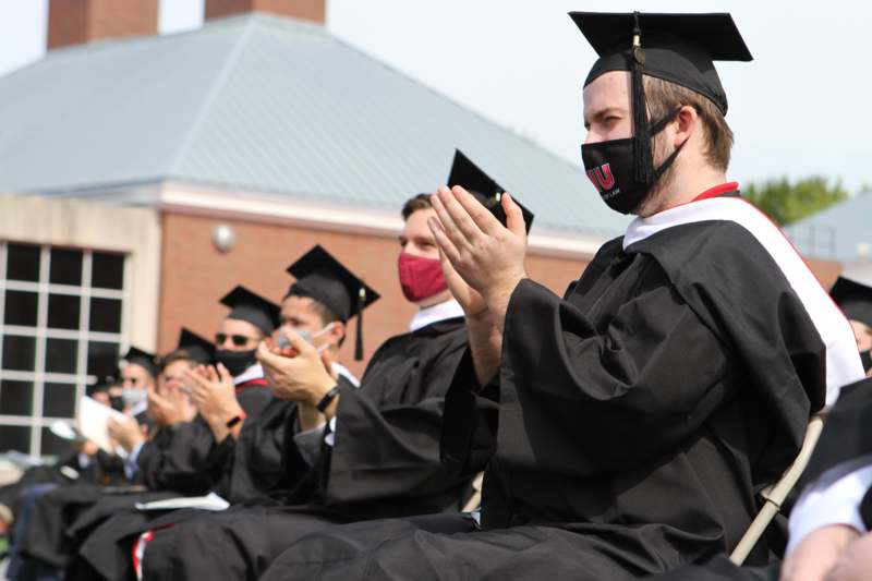a group of people in graduation gowns and cap and gowns with masks