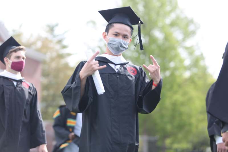 a man wearing a cap and gown holding up a diploma