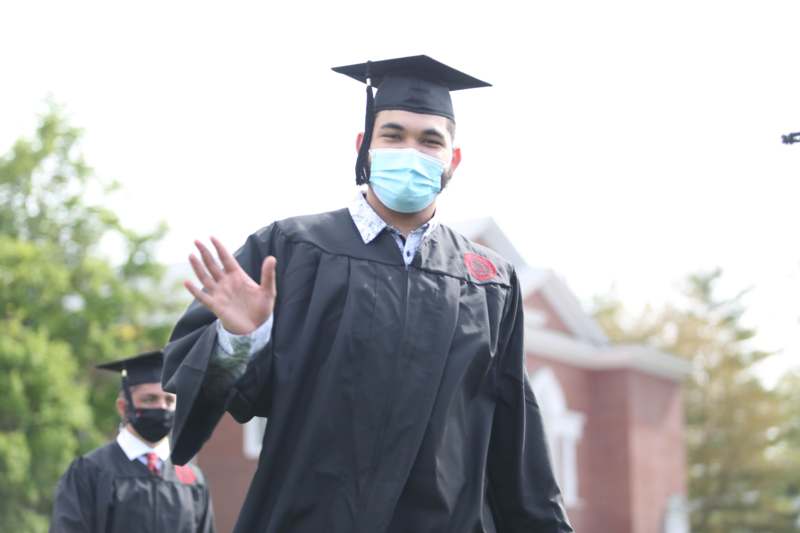 a man wearing a mask and cap and gown