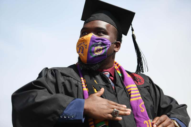 a man wearing a graduation gown and mask