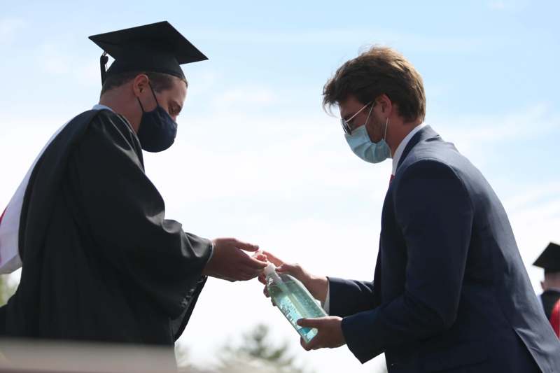 a man in a cap and gown holding a bottle of alcohol