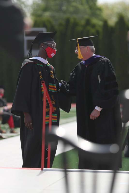 a man wearing a mask and a graduation gown