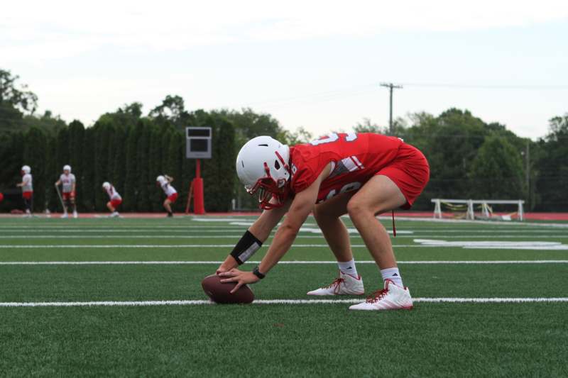 a football player kneeling on a field with a ball