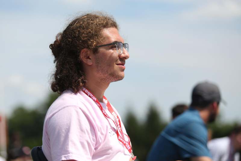 a man with long curly hair wearing glasses and a white shirt