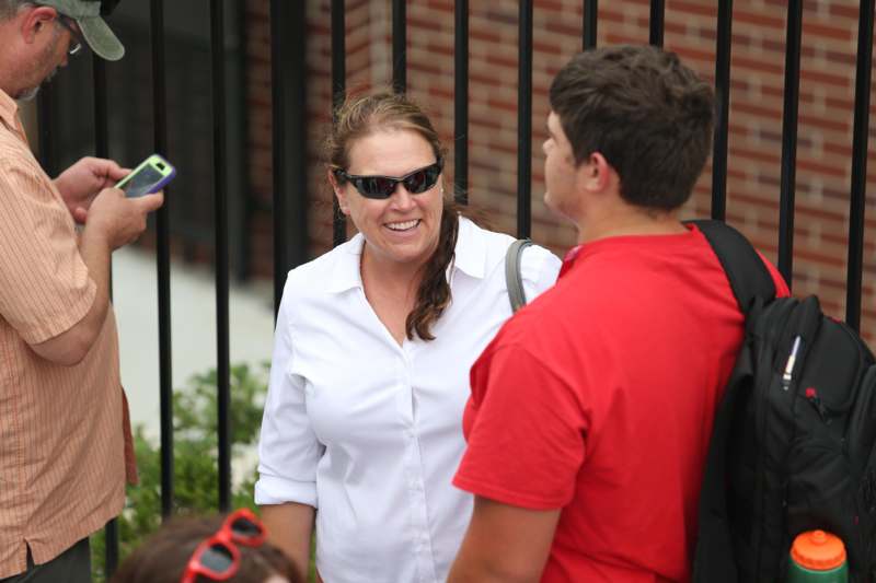 a woman in sunglasses standing next to a man in red shirt