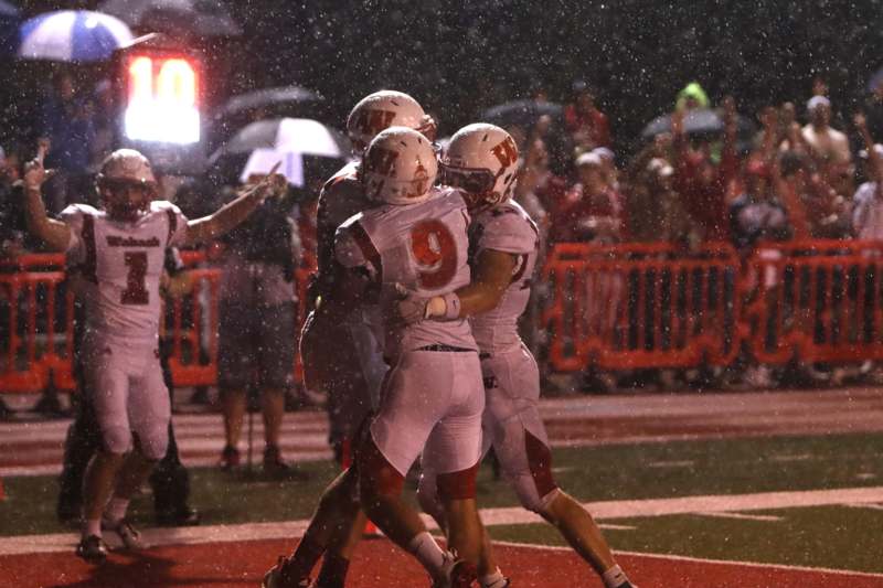 a group of football players celebrating in the rain