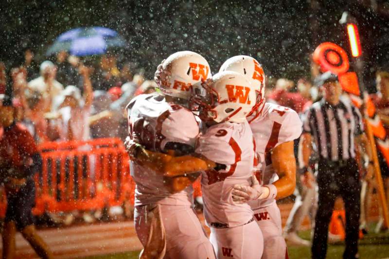 a group of football players hugging in the rain
