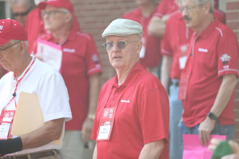 a man in red shirt and cap standing in front of other men