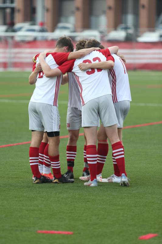 a group of men in sports uniforms huddling on a field