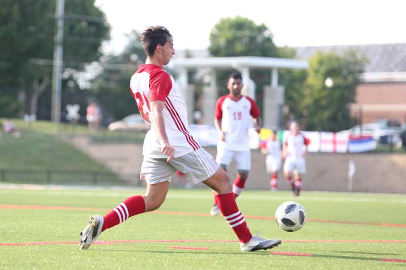 a man in a red and white uniform kicking a football ball