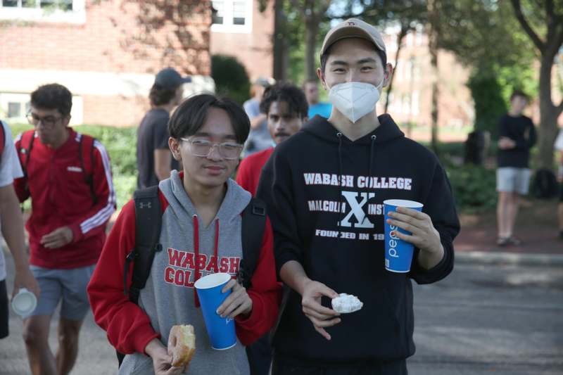 a group of people wearing face masks and holding drinks and donuts