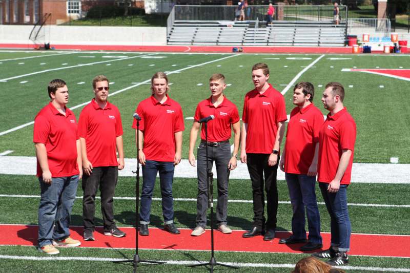 a group of men in red shirts standing on a football field