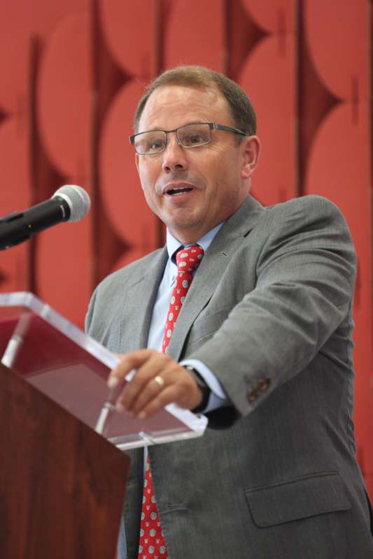 a man in a suit and tie speaking into a microphone