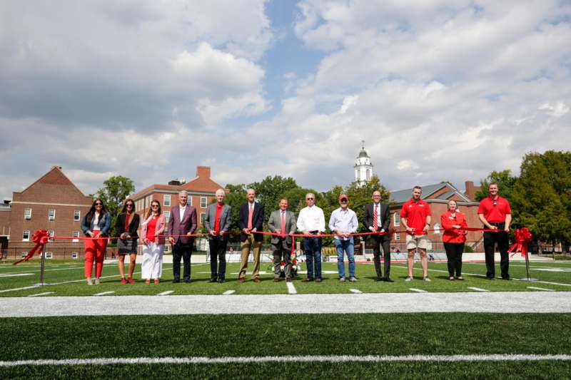a group of people holding a red ribbon on a football field