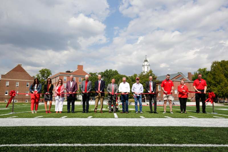 a group of people holding a red ribbon on a football field